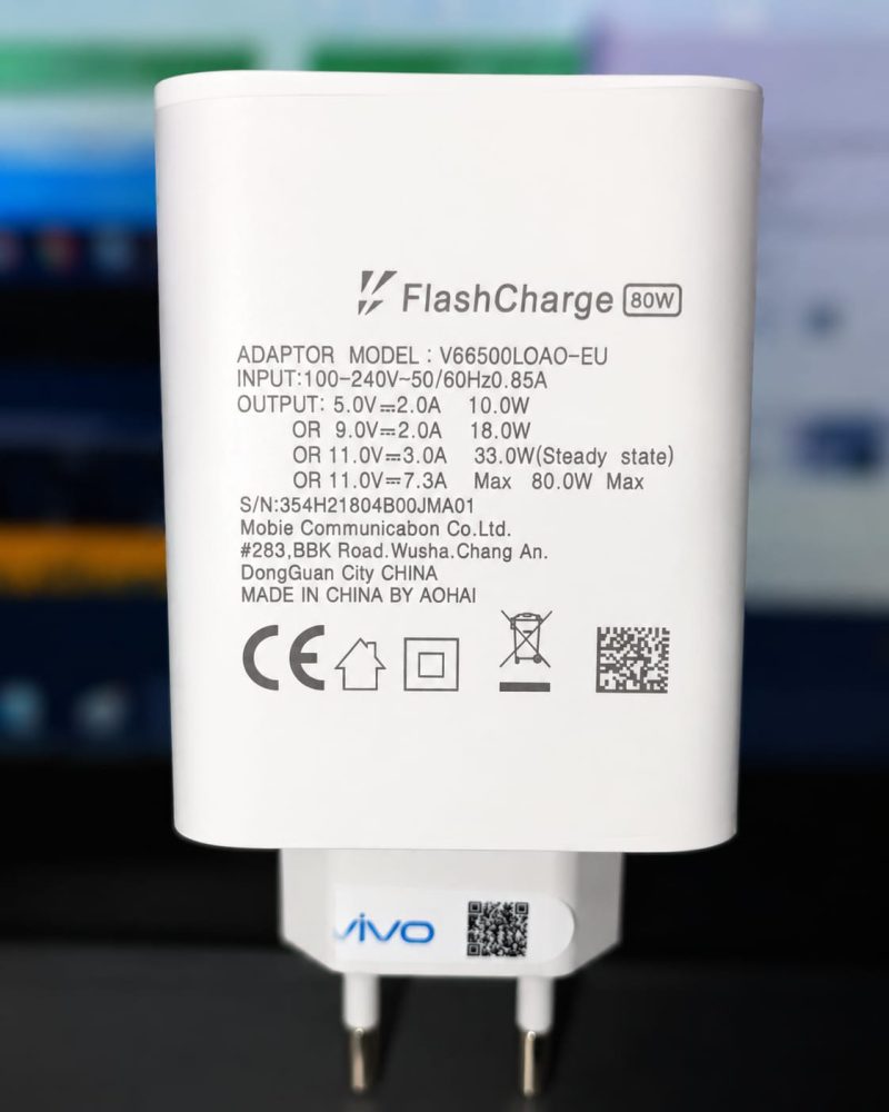 Vivo FlashCharge 65W Mobile Charger Close-up of a white FlashCharge 80W mobile charger with technical specifications, showing input and output details along with the "vivo" logo and certification symbols.